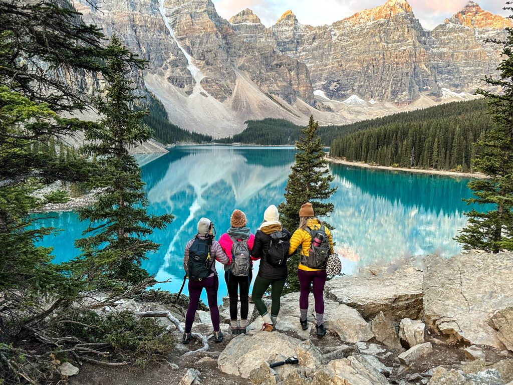 4 girls in winter clothes standing at Moraine Lake at sunrise