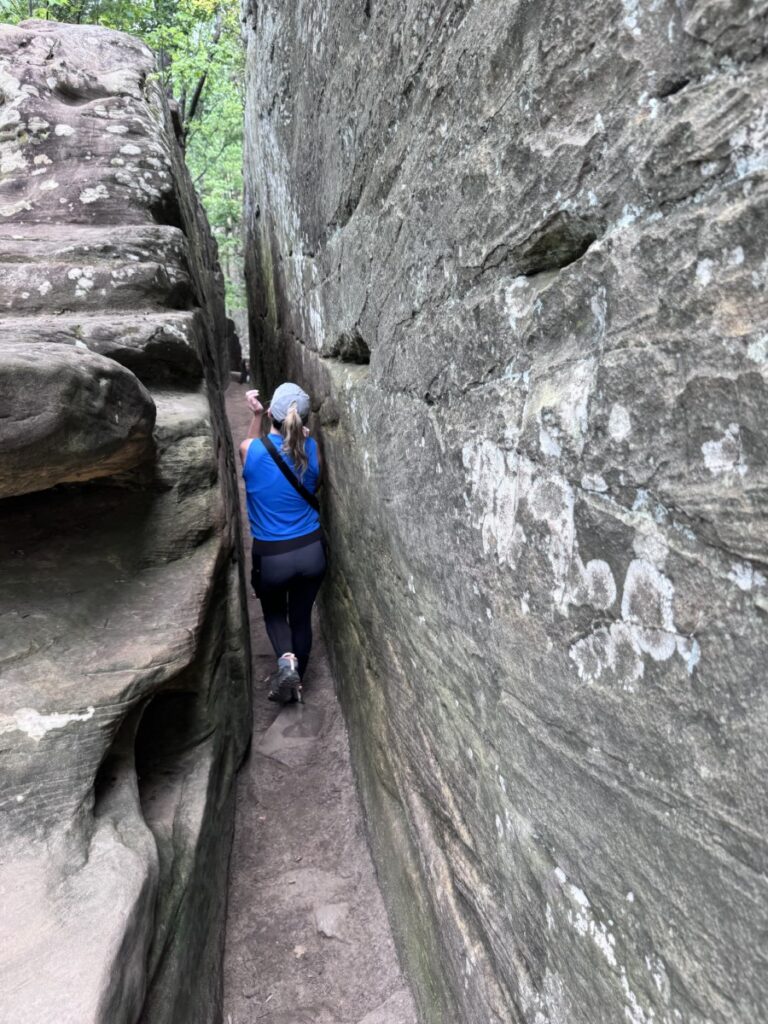 Girl walking through narrow rock space at red River gorge natural bridge