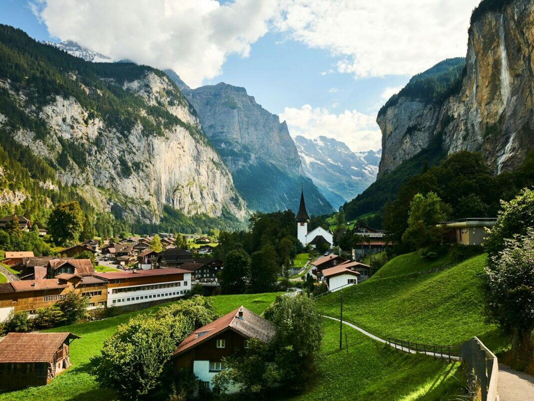 Scenic landscape of Lauterbrunnen Valley with traditional Swiss chalets and dramatic mountain cliffs in summer.