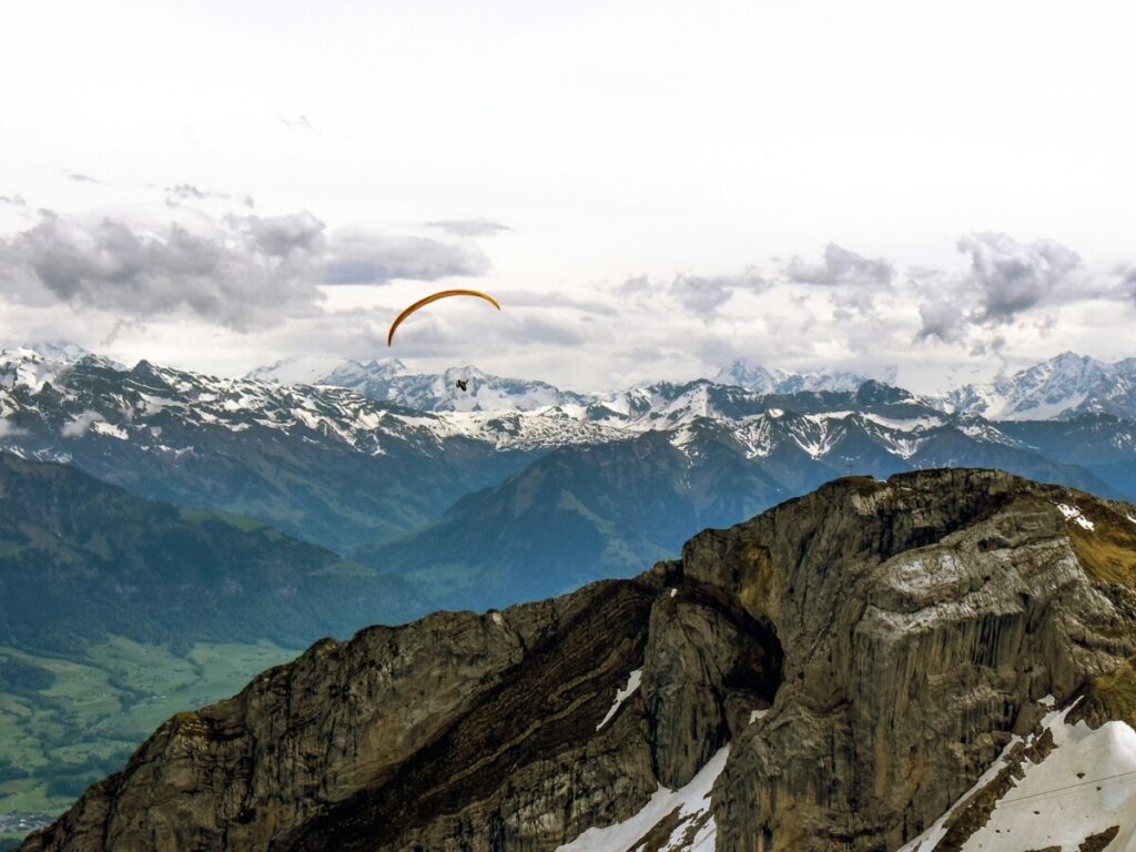 a paraglider is flying over a mountain range